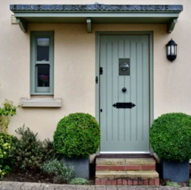 Sage green composite front door fitted to a home