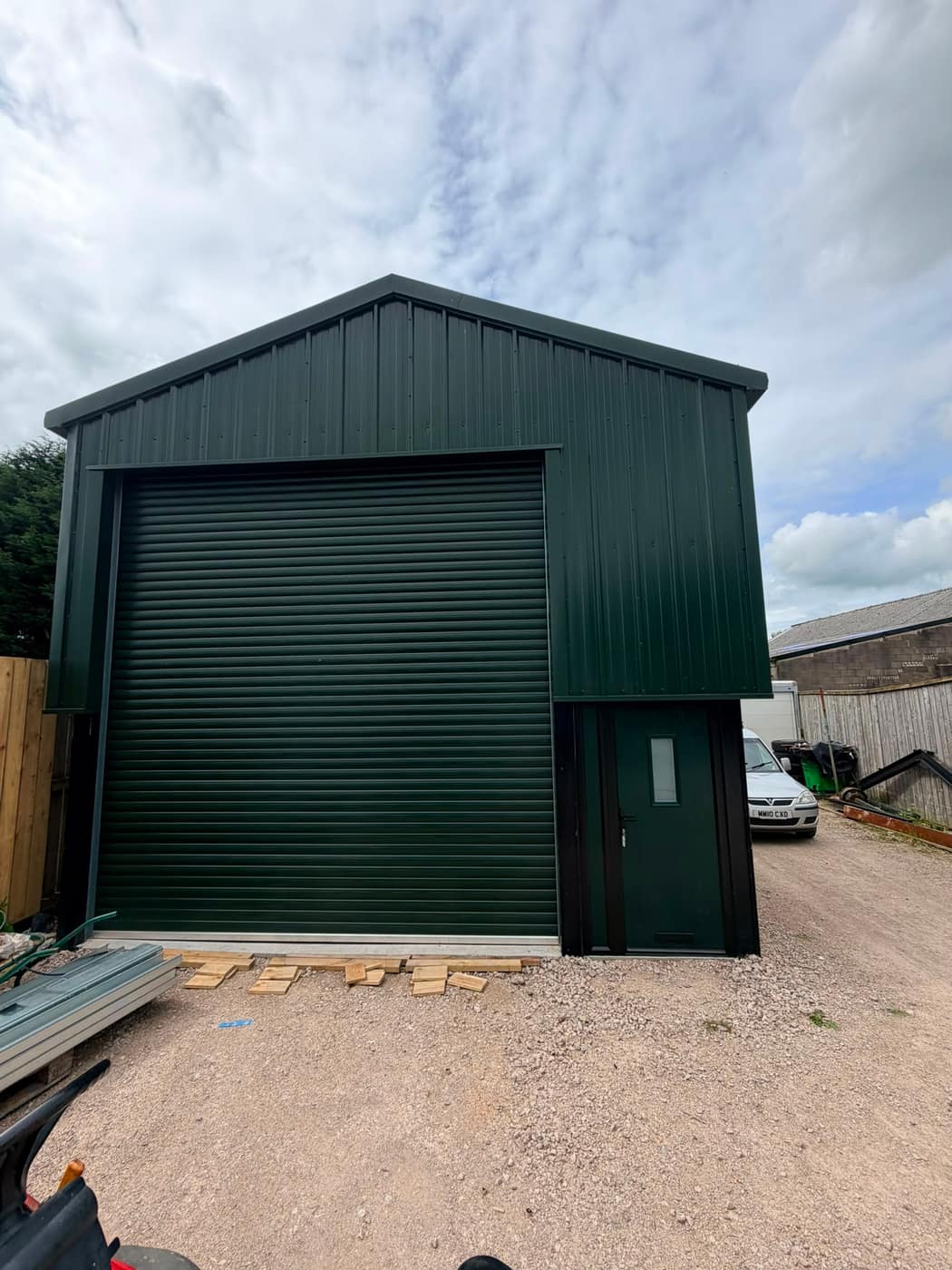 Green steel industrial unit with roller shutter and personnel door