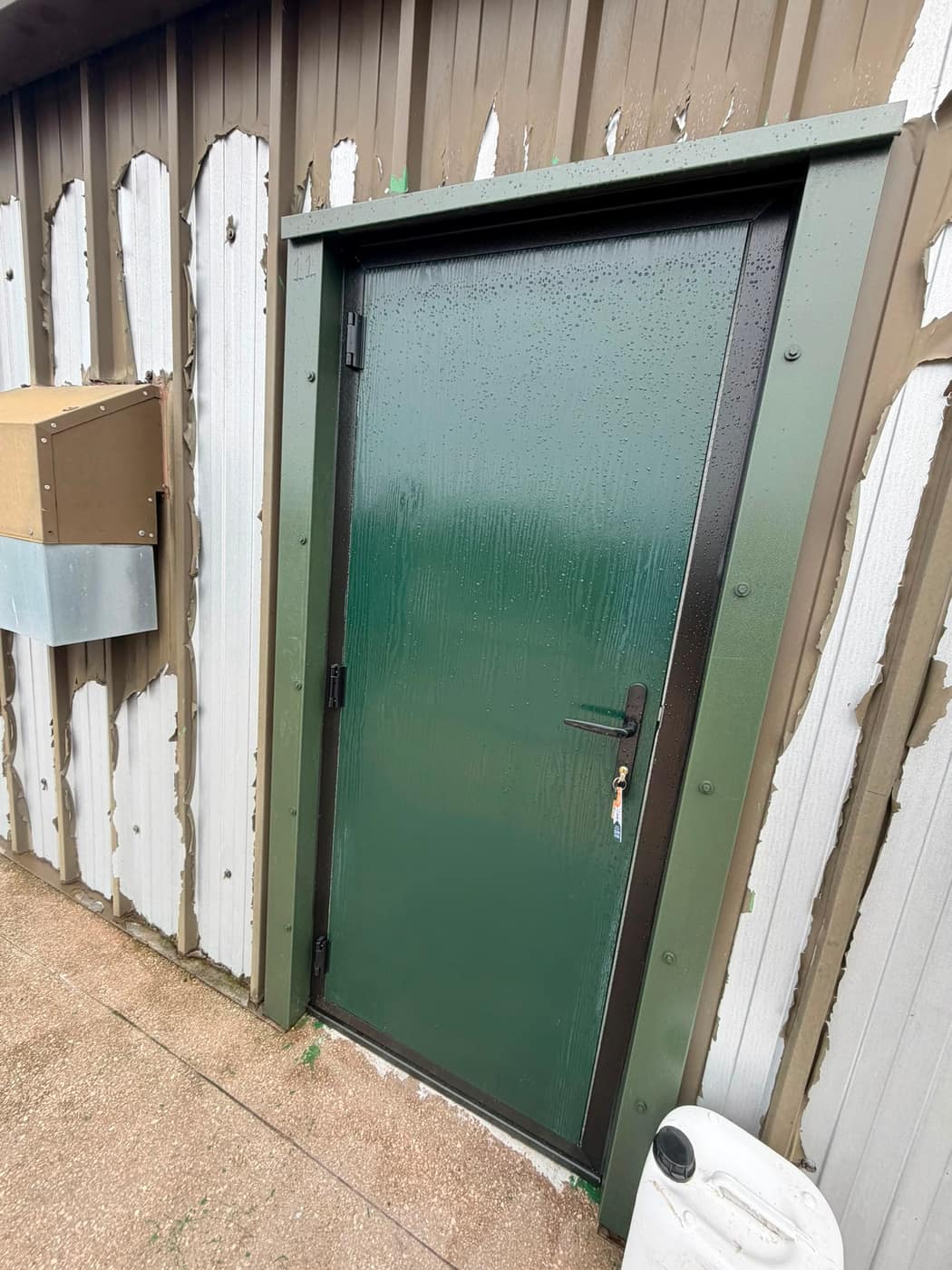 Green steel security door fitted to an industrial building