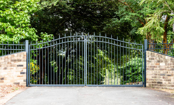 Tall wrought iron driveway gates set within hedging